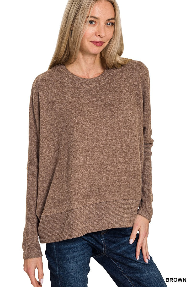 Woman wearing a brown sweater and blue jeans on a white background