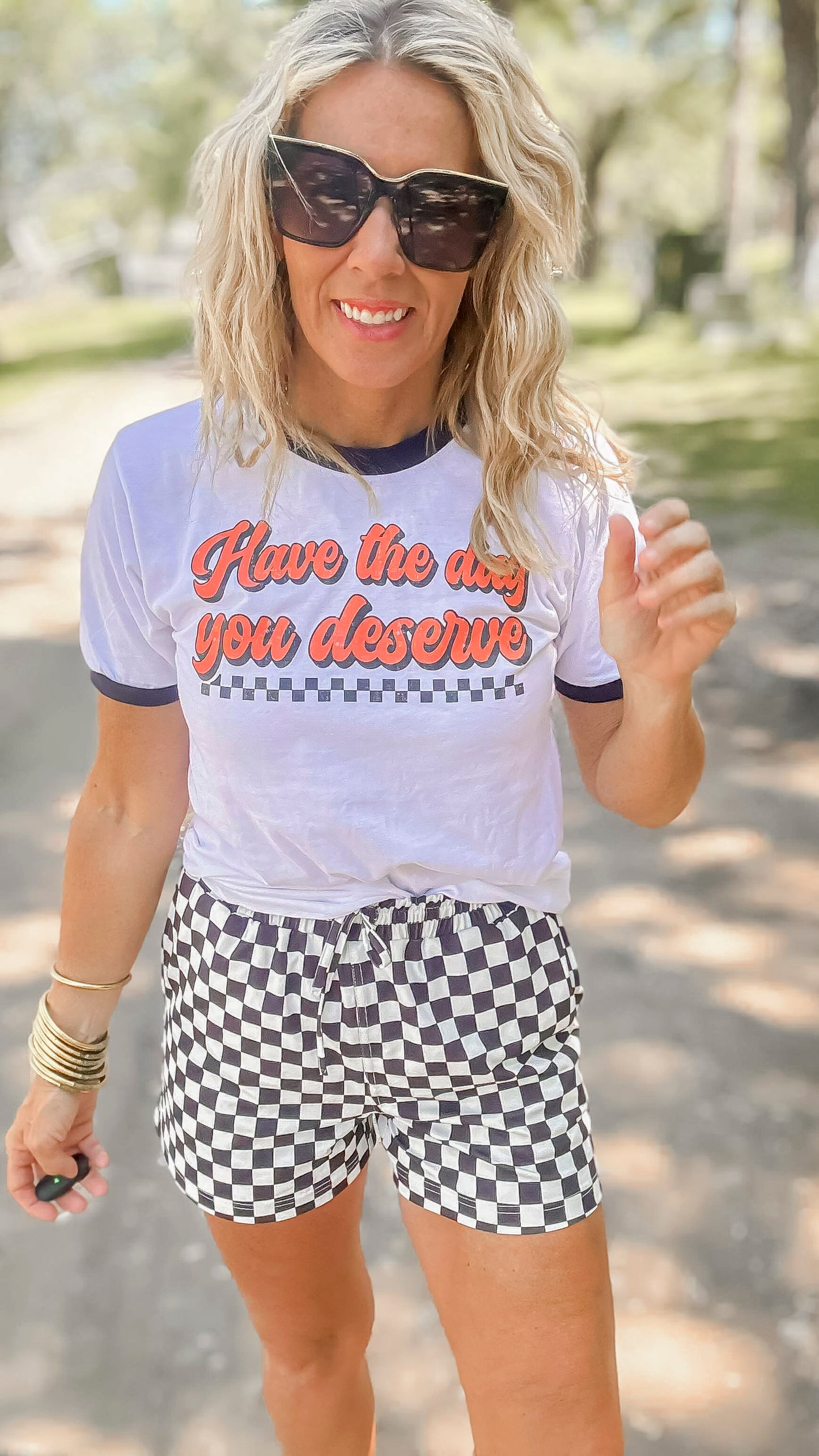 Woman wearing a graphic t-shirt and checkered shorts outdoors