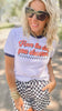 Woman wearing a white t-shirt with text and checkered shorts outdoors