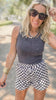 Woman wearing a ribbed tank top and checkered shorts outdoors.