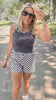 Woman wearing a sleeveless top and checkered shorts outdoors.