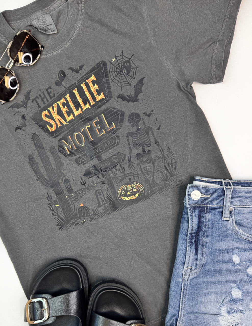 Dark graphic tee with haunted motel scene and desert skeleton artwork for Halloween vibes.