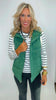Woman wearing a green puffer vest over a striped shirt on a white background