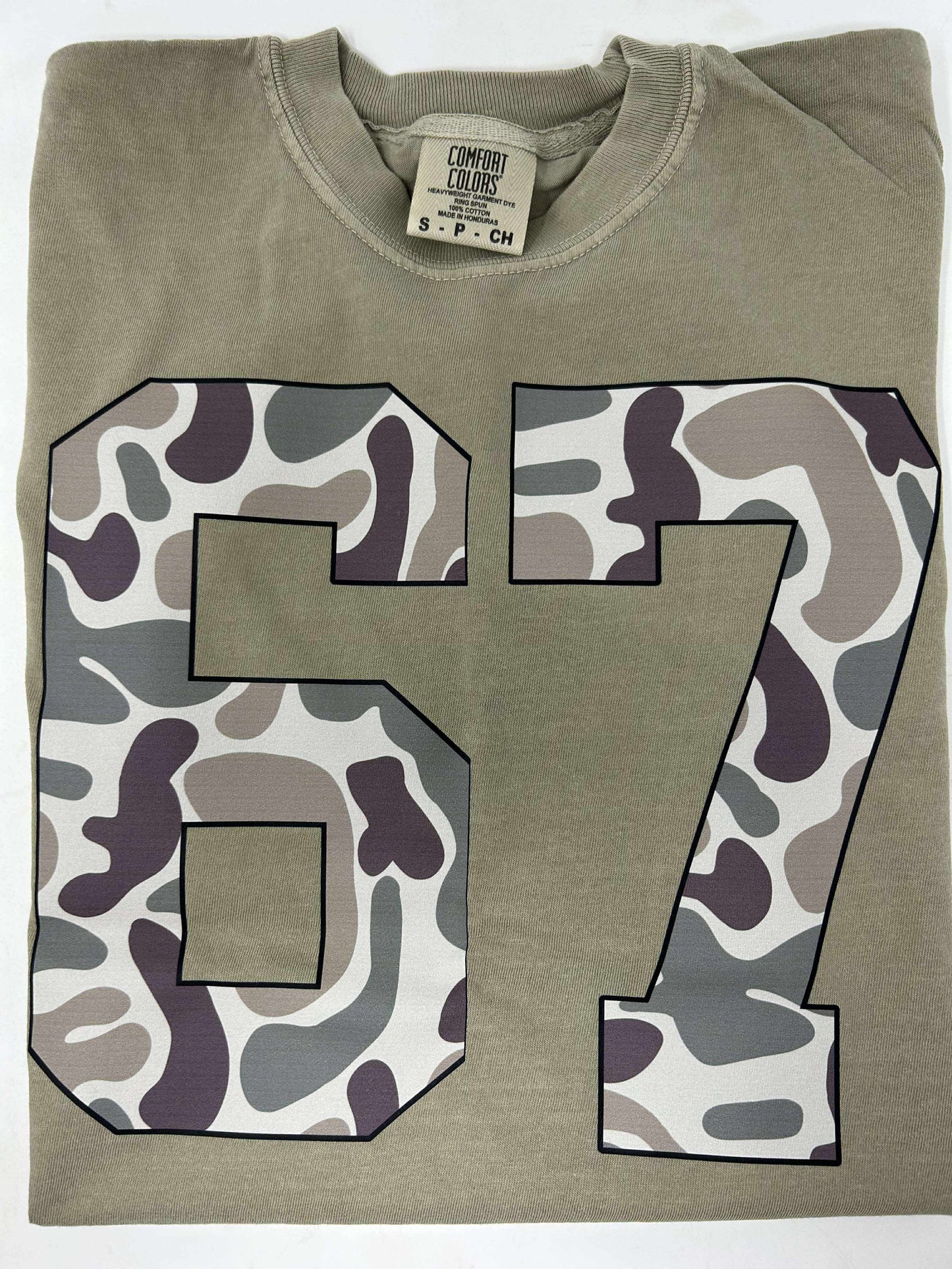 Folded green sweatshirt with camouflage number '67' on a white background