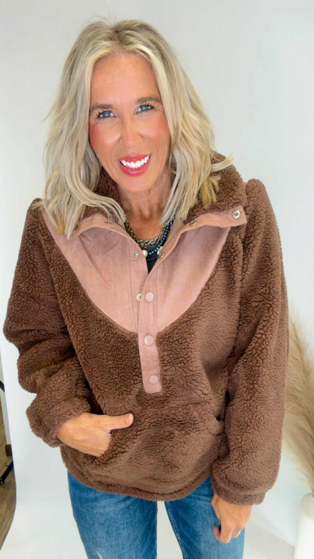 Woman wearing a brown fleece pullover with a sheer panel over a white background