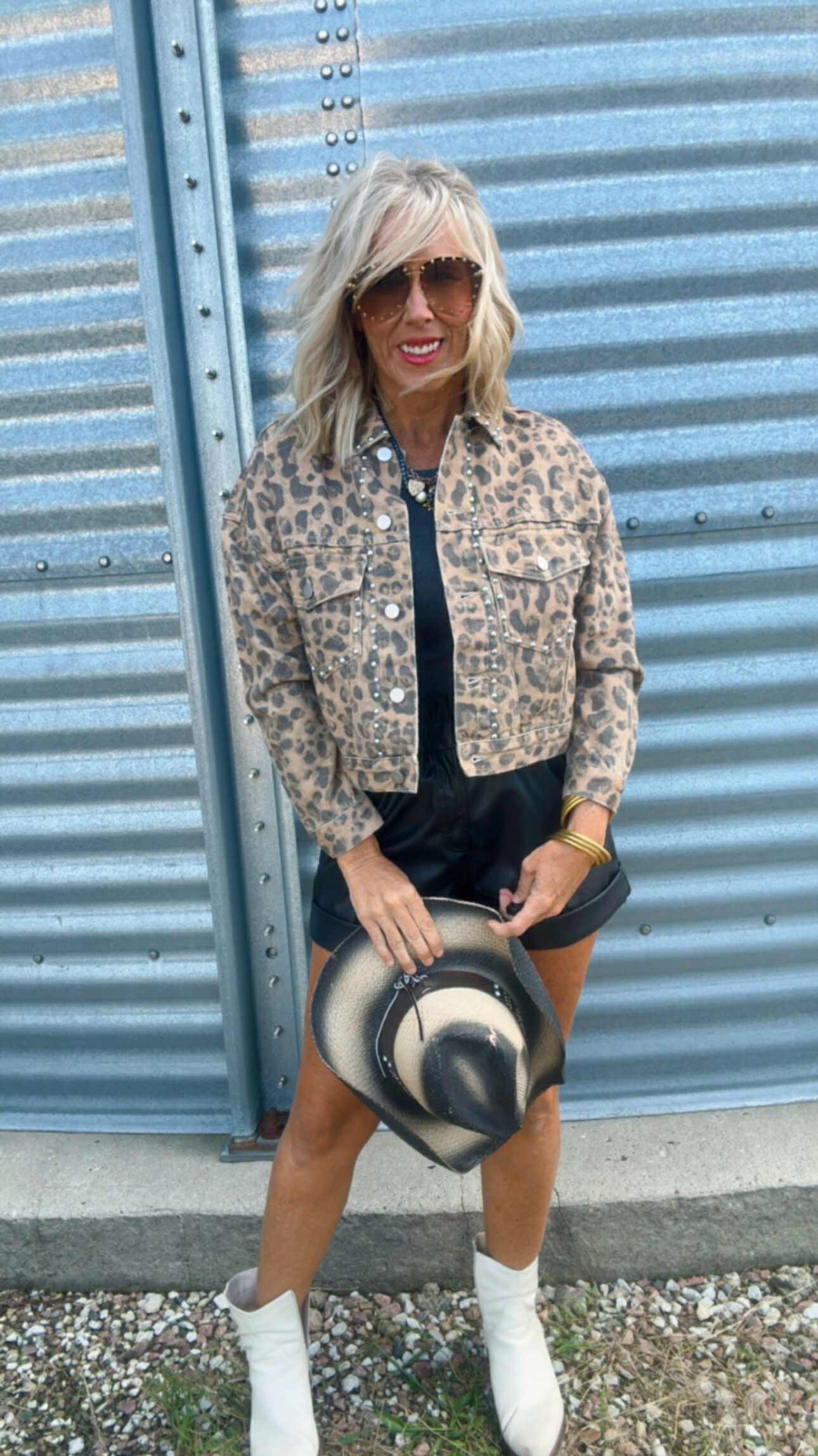 Woman holding a hat in front of a corrugated metal wall