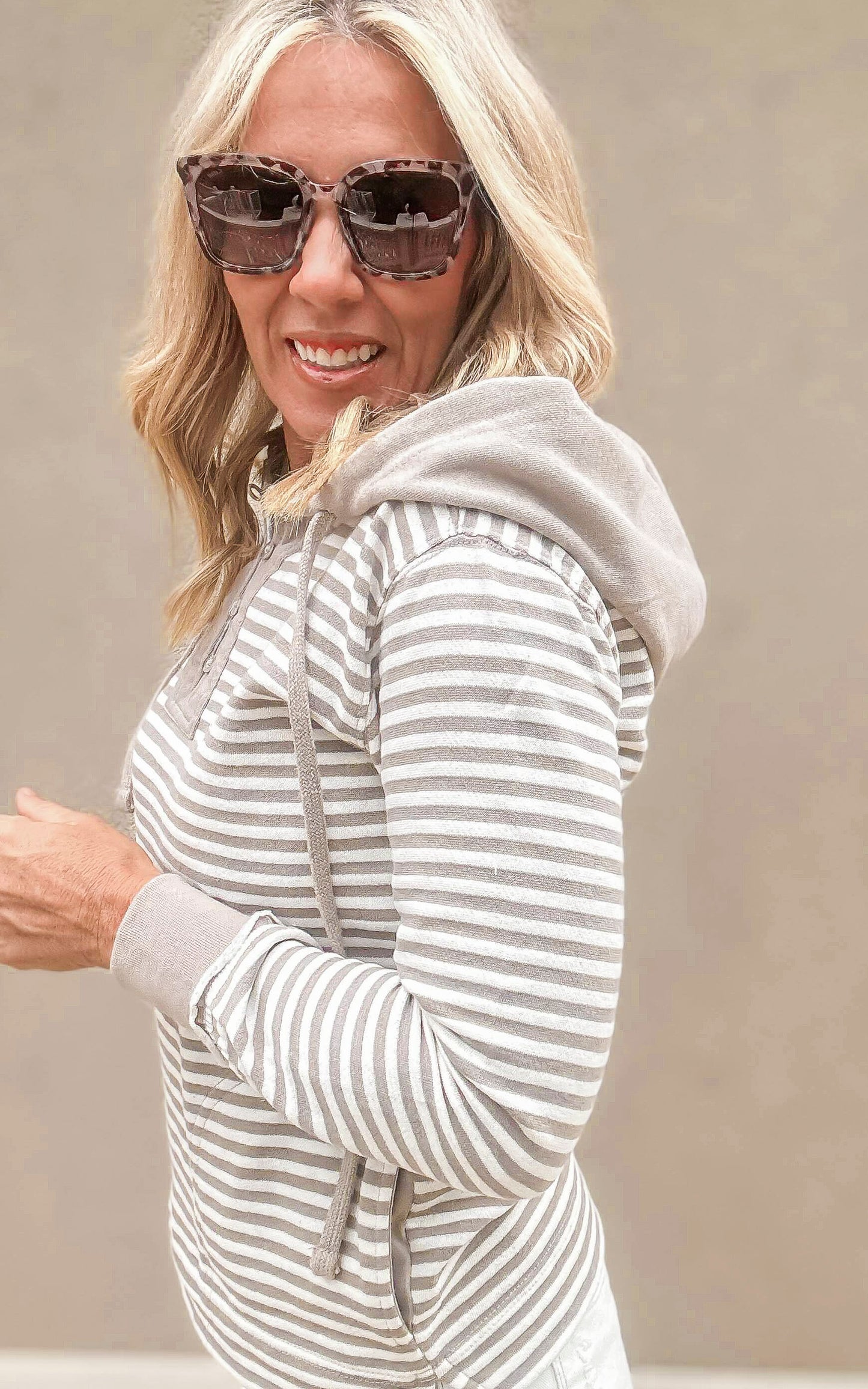 Striped long-sleeve henley hoodie with cuffed sleeves and drawstring hood, paired with white frayed shorts for a laid-back look.