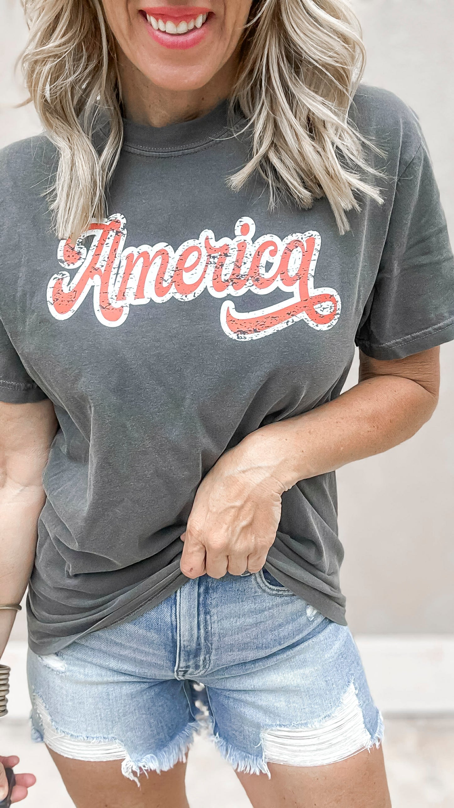 Charcoal gray garment-dyed t-shirt featuring distressed “America” lettering.