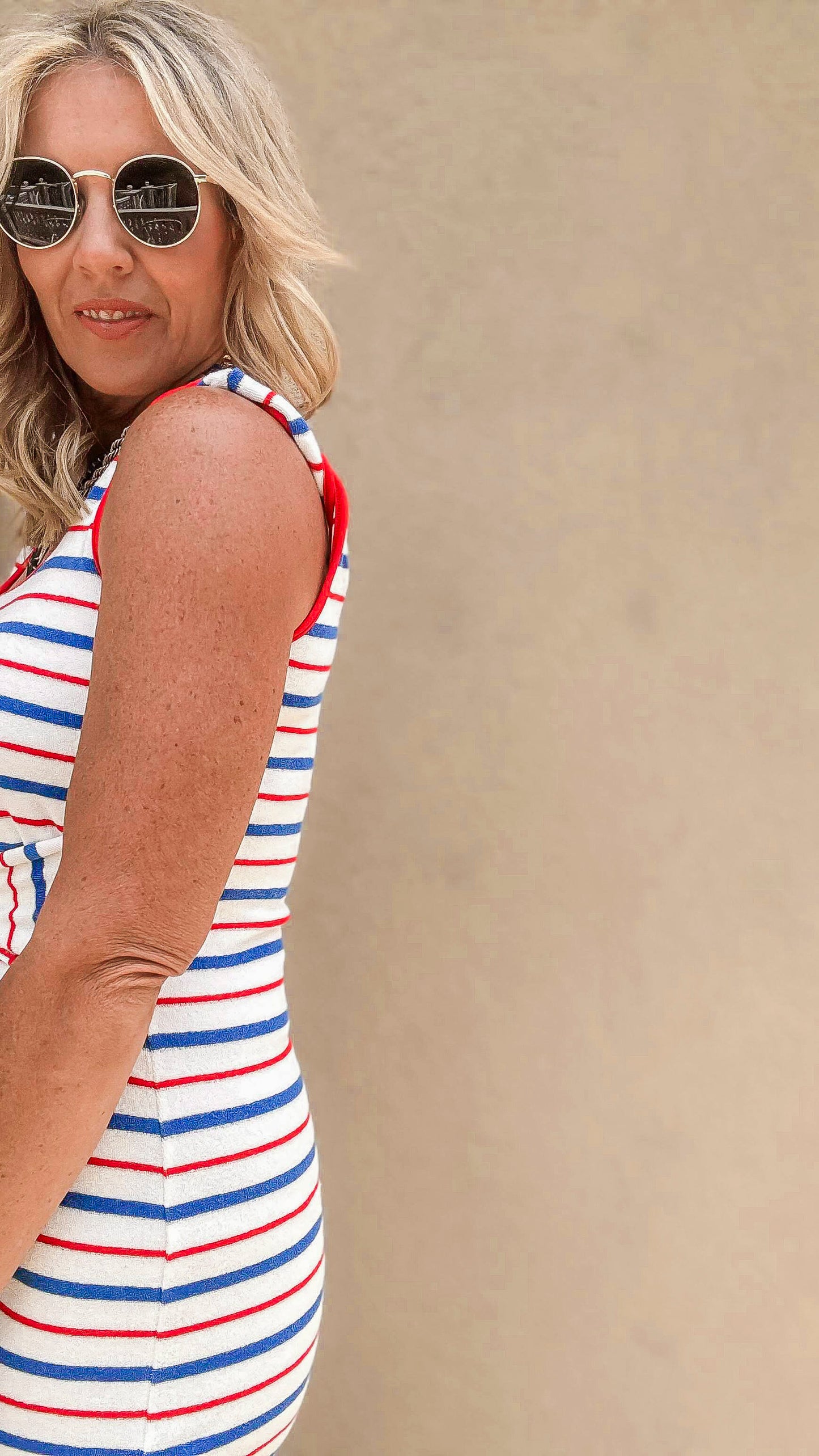 Model wearing a festive red, white, and blue striped tank dress with a belted waist.