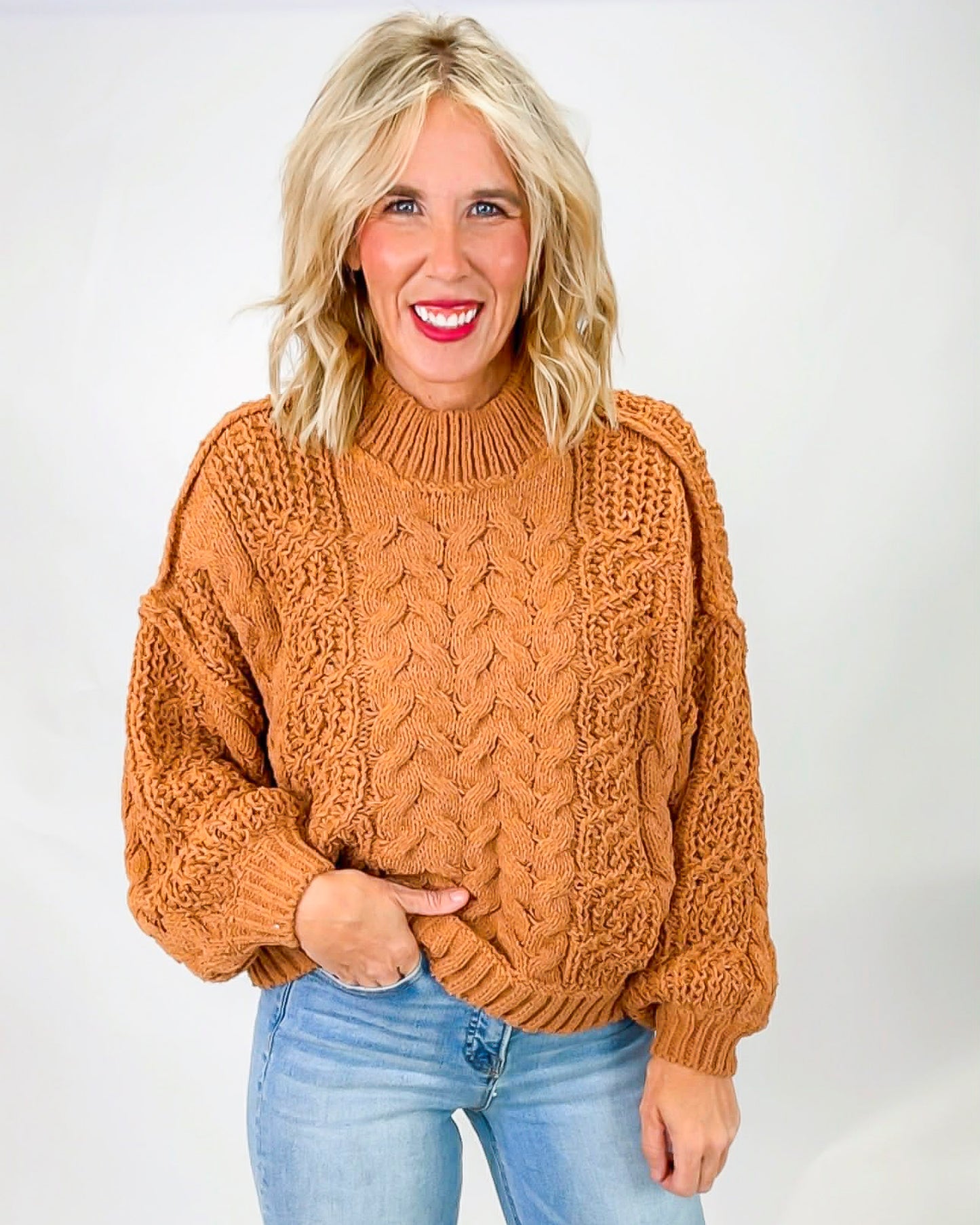 Woman wearing topez sweater against white backdrop