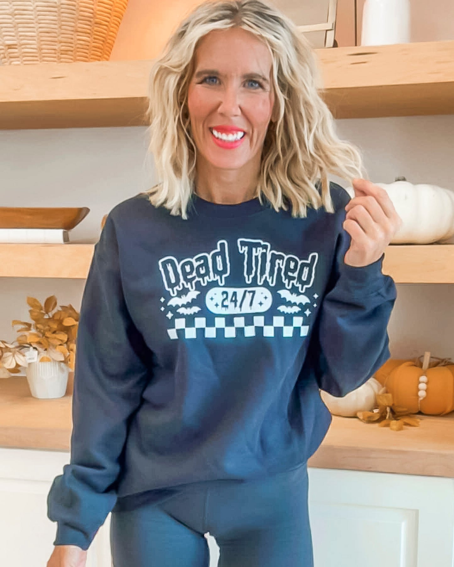 Woman wearing a navy sweatshirt with text and graphics in a kitchen setting