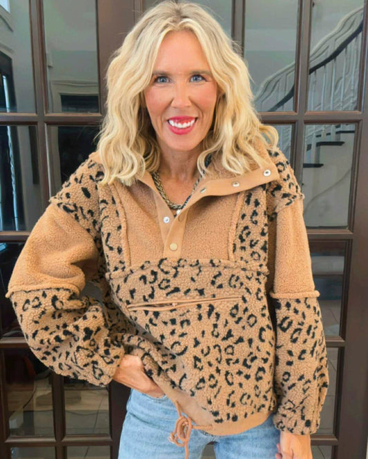 Woman wearing a beige leopard print pullover with a blurred background