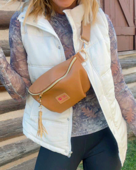 Person wearing a white puffer vest and carrying a tan crossbody bag on wooden steps.