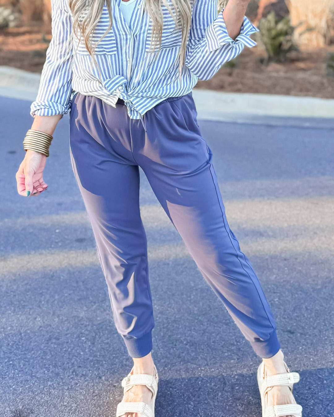 Person wearing a blue and white striped shirt and blue pants on a road.