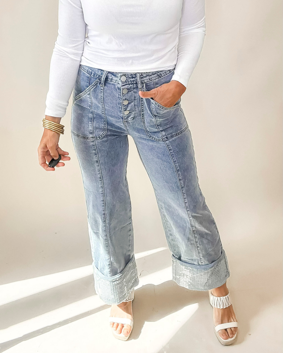 Person wearing light blue jeans and a white long-sleeve top against a plain background