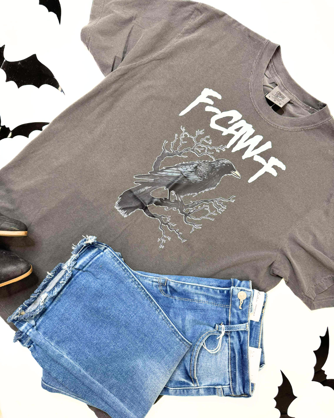 Gray t-shirt with a graphic design and text, paired with denim shorts on a white background.