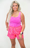 Woman wearing a pink tank top and checkered shorts on a white background