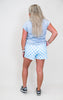 Woman wearing a light blue t-shirt and checkered shorts on a white background