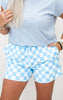 Person wearing a light blue t-shirt and checkered shorts on a plain background