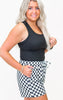 Woman wearing a black tank top and checkered skirt on a white background