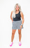Woman wearing a black tank top and checkered shorts on a white background
