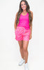 Woman wearing a bright pink tank top and checkered shorts on a white background