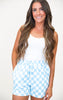 Woman wearing a white tank top and light blue checkered shorts on a white background