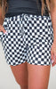 Person wearing black and white checkered shorts on a plain background