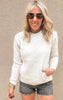 Raelynn Cloud Fleece crewneck in a heathered oatmeal hue, styled simply with distressed denim shorts.