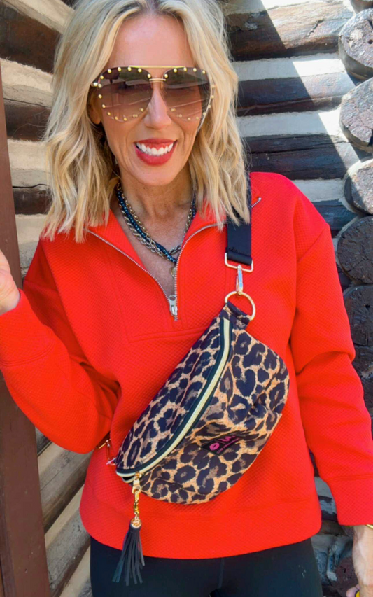 Woman wearing a red jacket with a leopard print bag against a wooden background