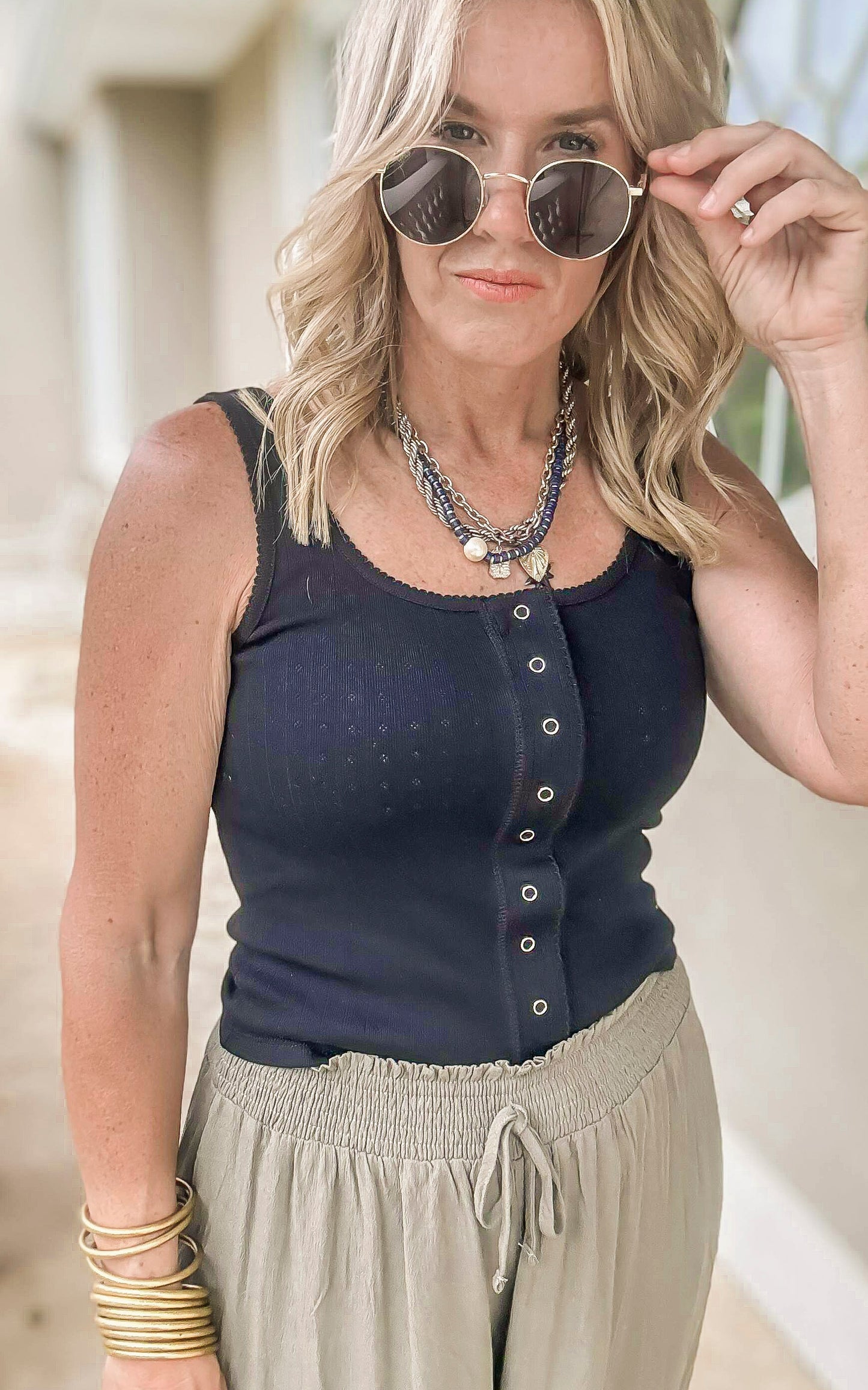 Casual black sleeveless top featuring snap buttons and soft stretch fabric.