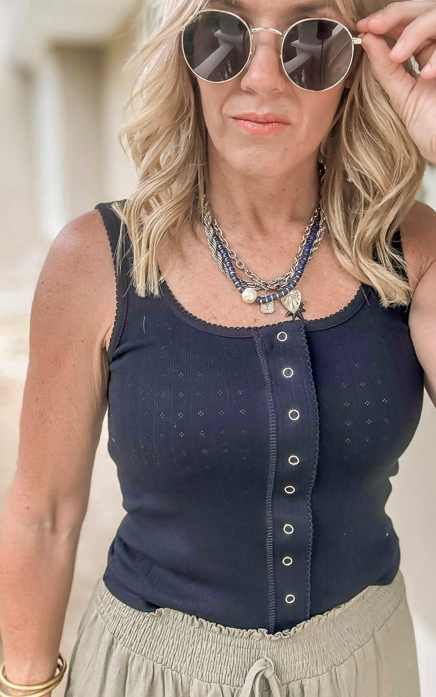 Black button-front tank top styled with olive green wide-leg drawstring pants.