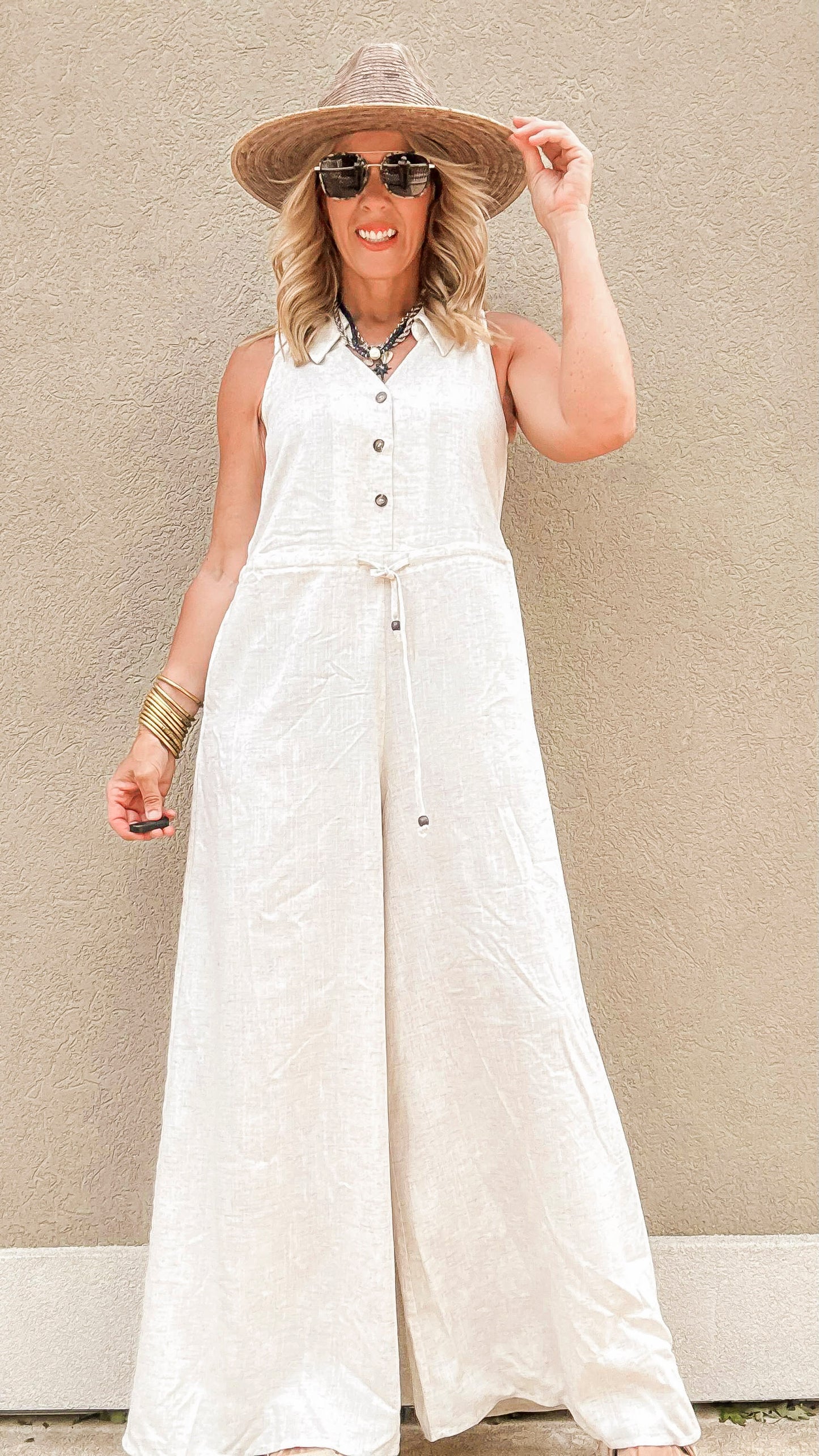 Lightweight sleeveless jumpsuit with button-down front and adjustable waist tie.