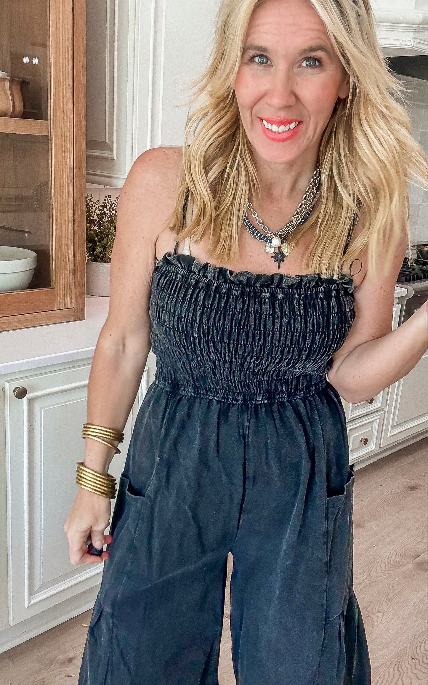 Comfortable and chic black strapless jumpsuit with a gathered top and flowy pant legs, paired with chunky sandals.