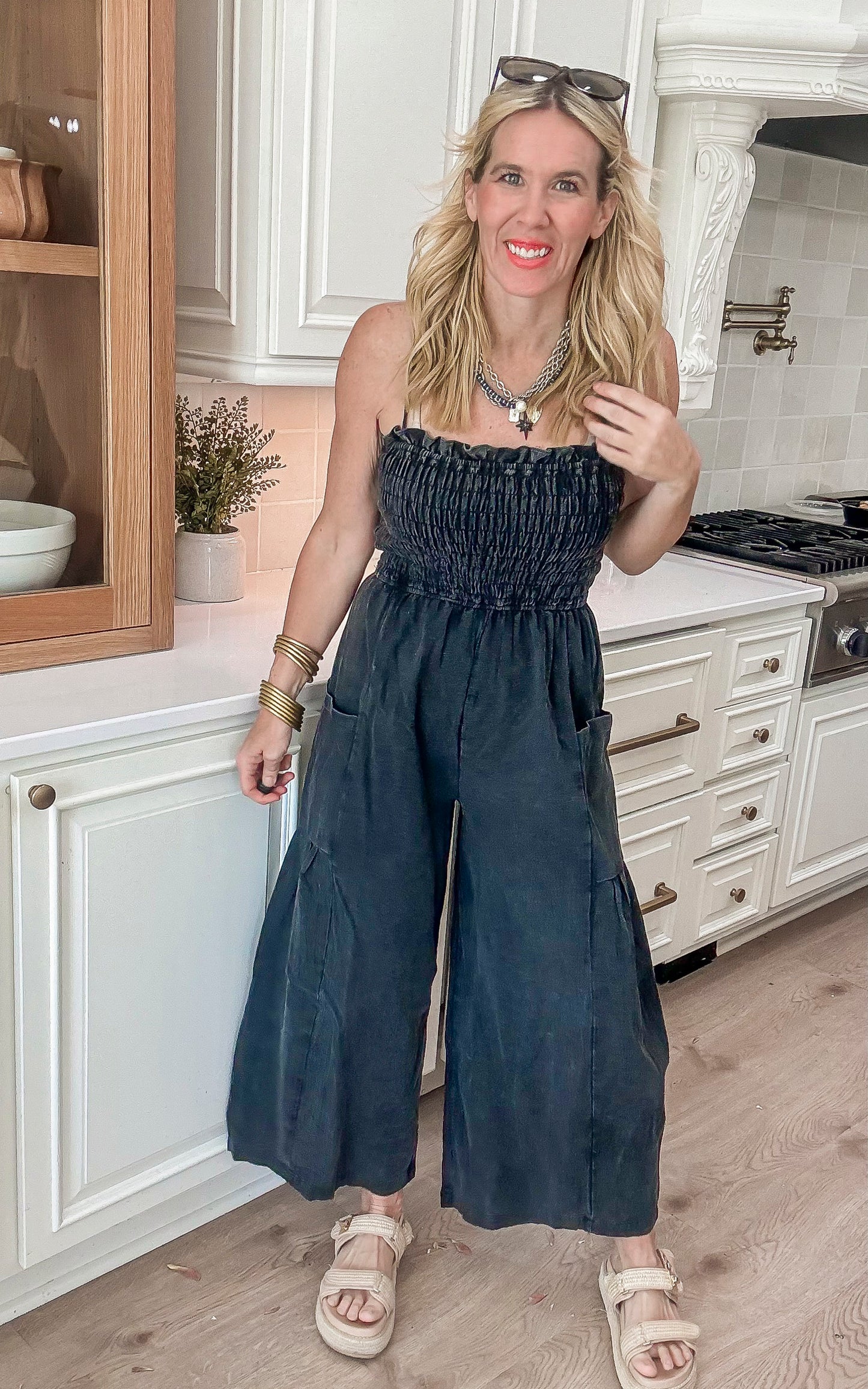 Lightweight smocked black jumpsuit with pockets and cropped wide legs, styled for a casual summer look.