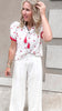 Embroidered gauze top with playful strawberry details, tucked into relaxed white pants for a soft and summery vibe.
