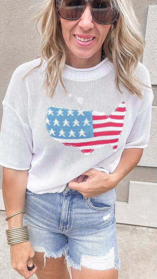 USA flag graphic sweater styled with distressed denim shorts.