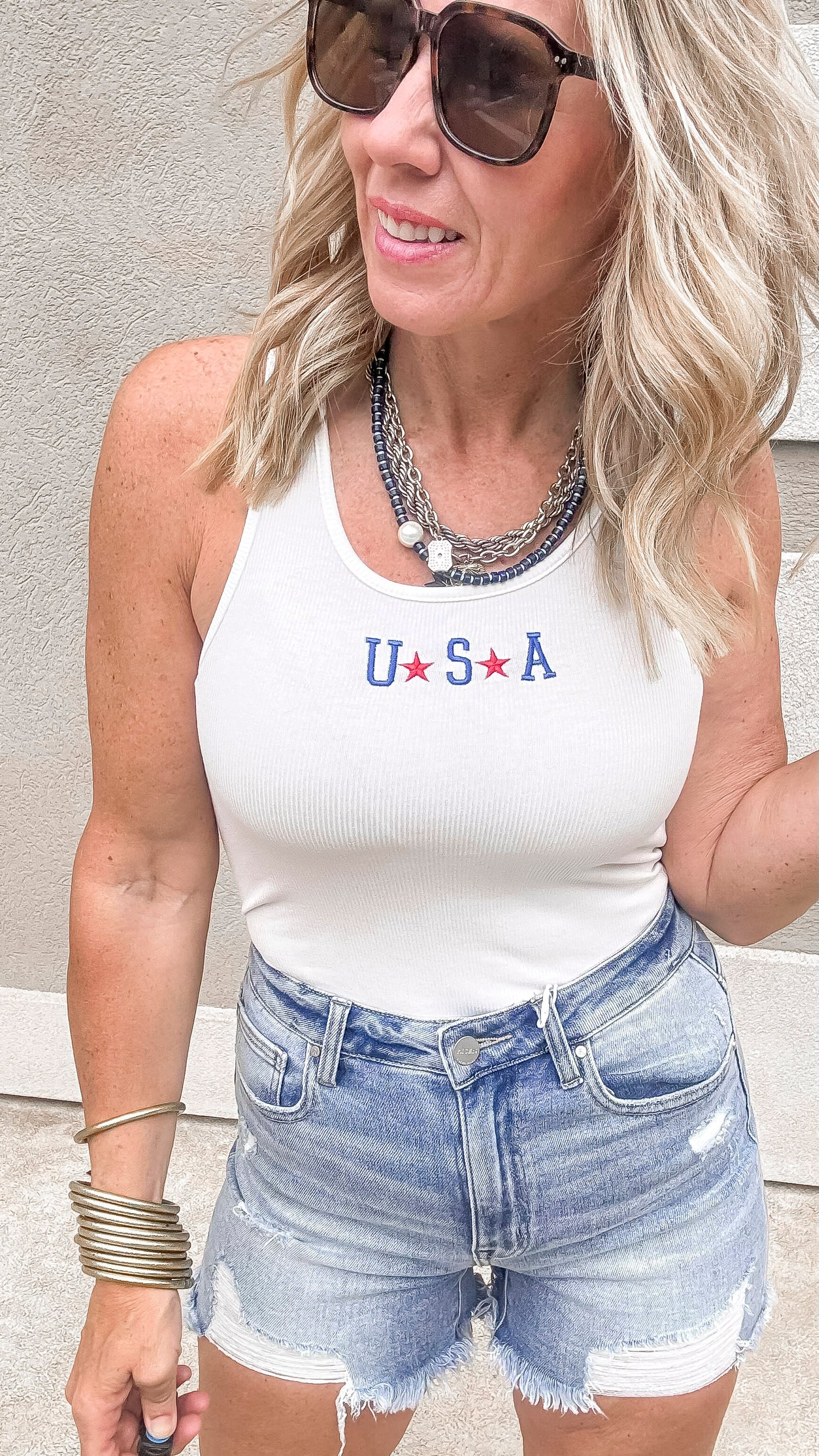 Sleeveless white bodysuit with USA detail and jean shorts outfit.