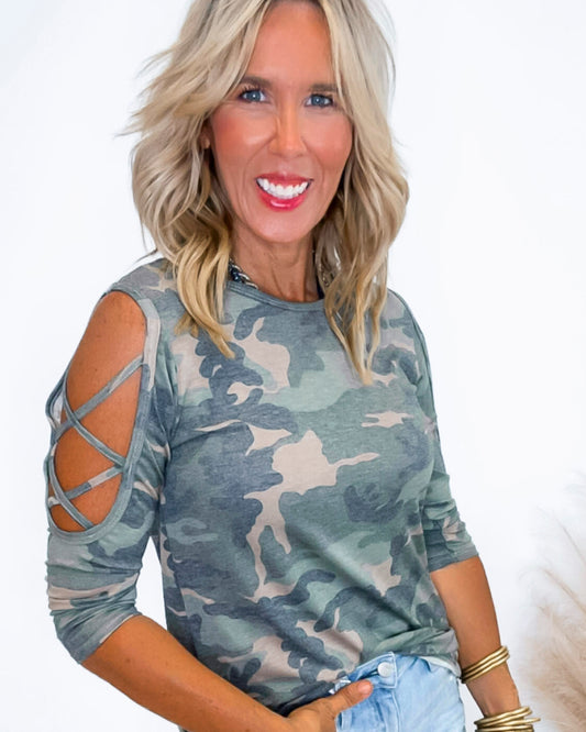 Woman wearing a camouflage top with cut-out sleeves on a white background