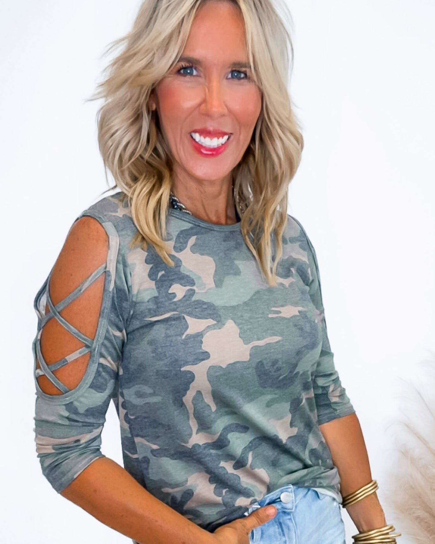 Woman wearing a camouflage top with cut-out sleeves on a white background