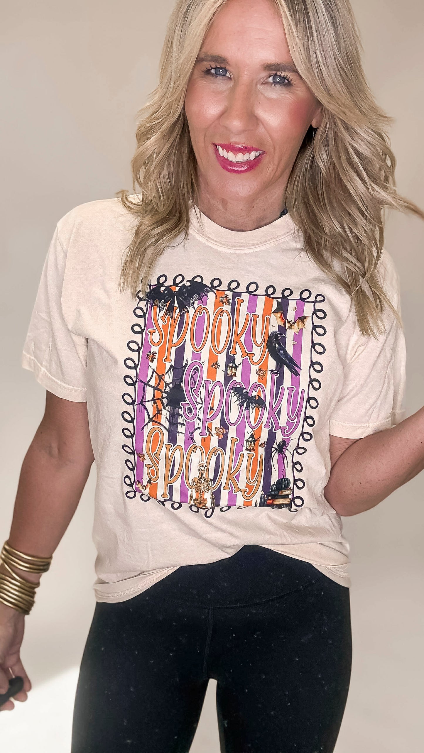 Woman wearing a beige t-shirt with 'Spooky' graphic design on a plain background