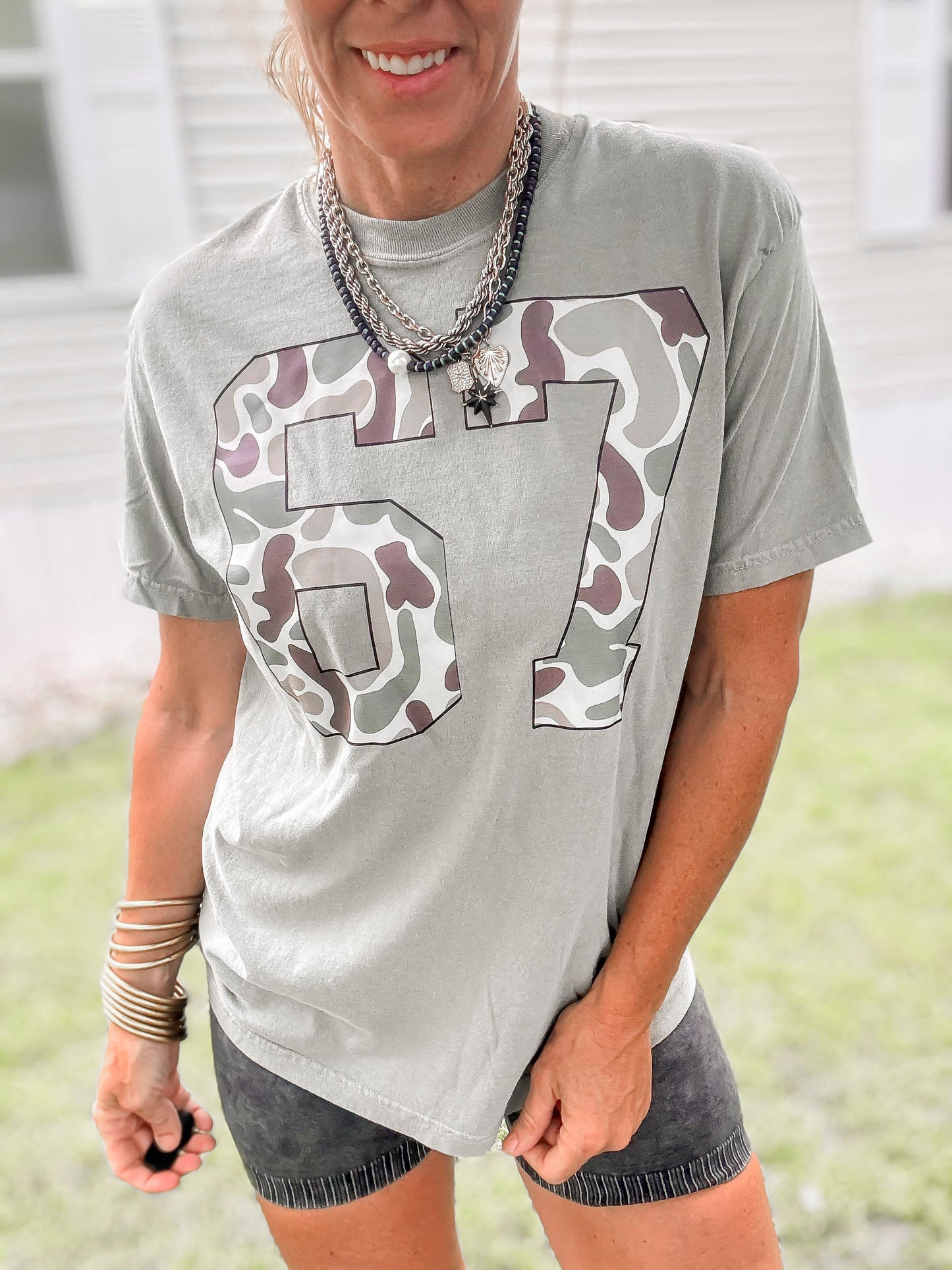 Person wearing a olive t-shirt with camouflage numbers outdoors