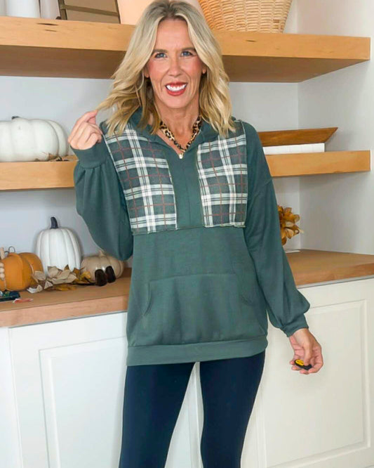 Woman wearing a green hoodie with plaid accents in a kitchen setting
