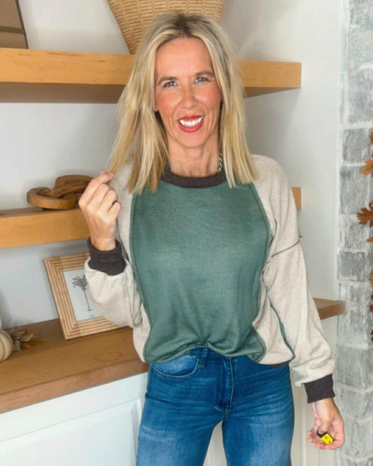 Woman wearing a green and beige sweater with blue jeans indoors.