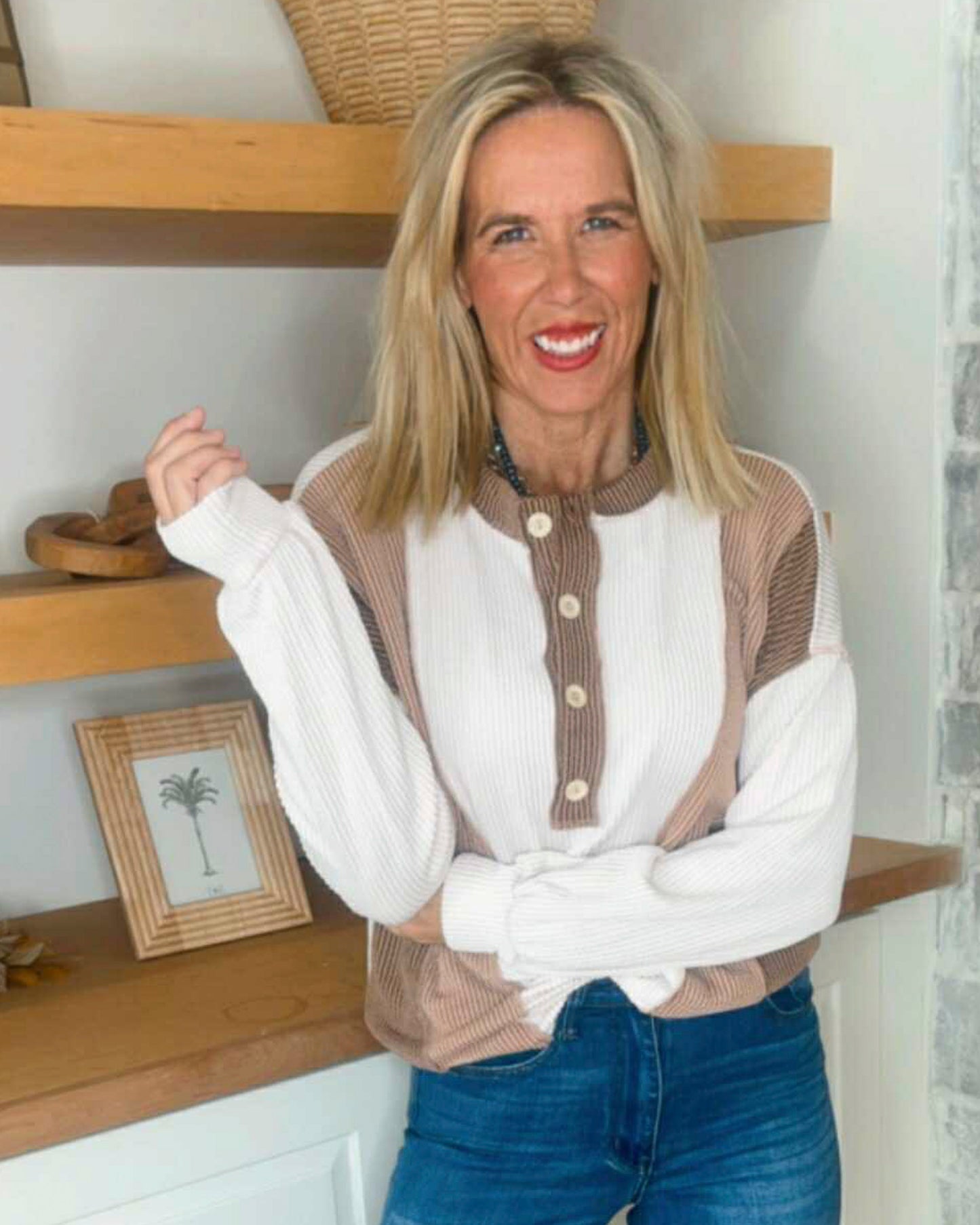 Woman wearing a white blouse with brown accents in a home setting