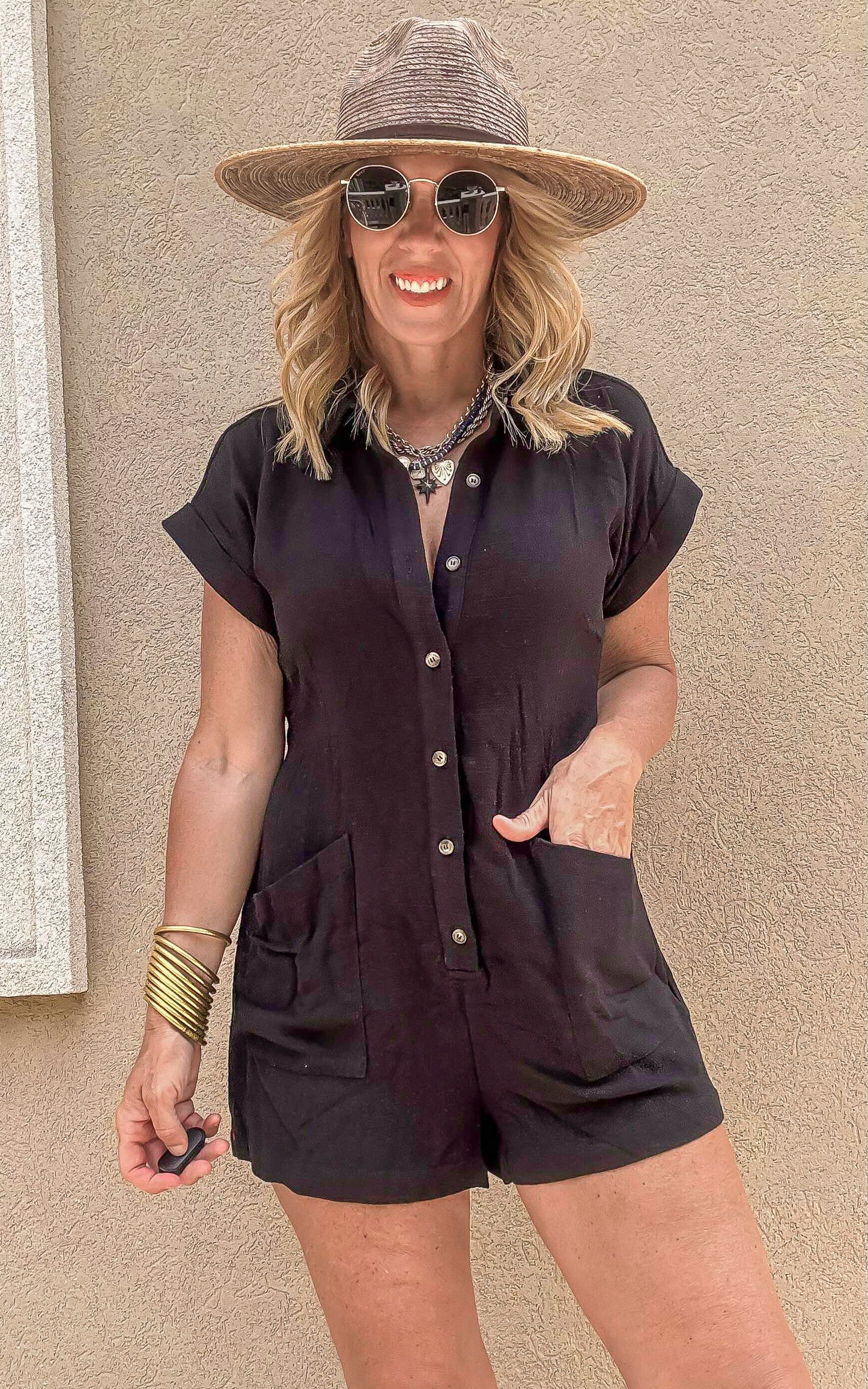 Casual black romper featuring cuffed sleeves, front buttons, and easy style.