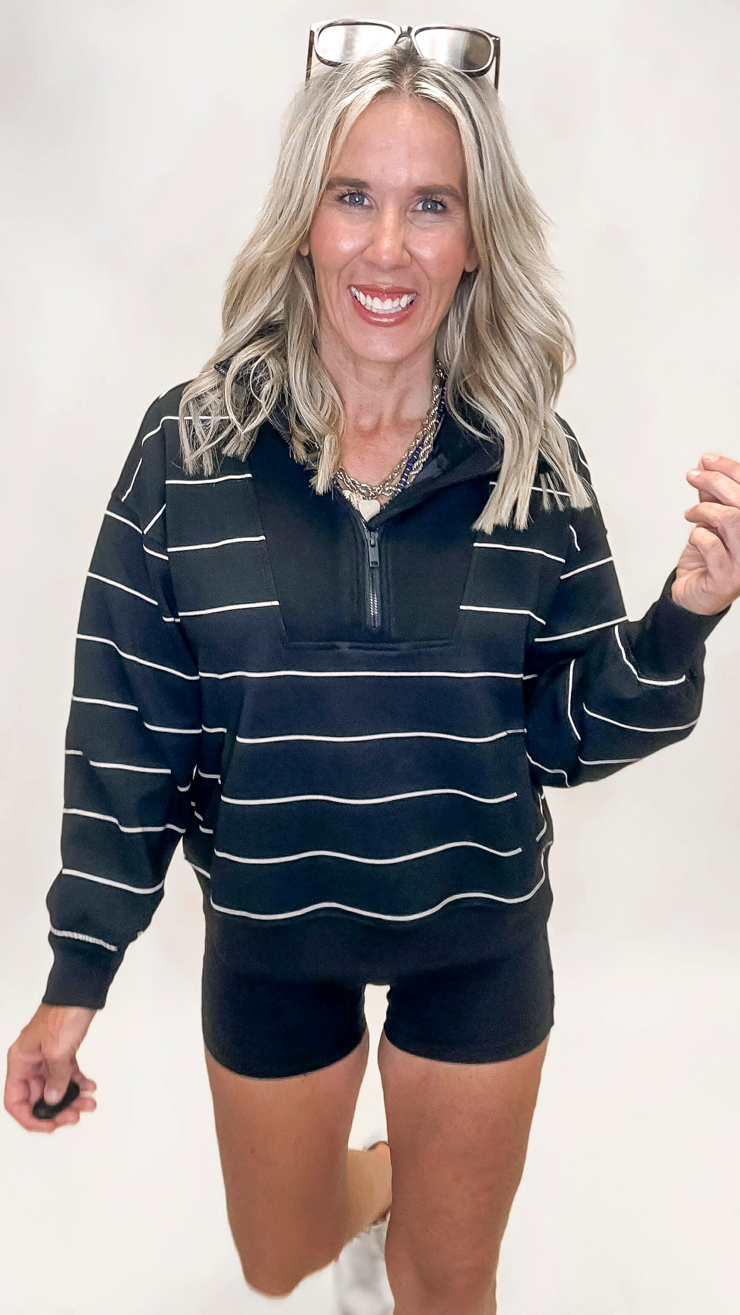 Black quarter zip pullover with thin white stripes and a mock neckline, featuring a relaxed fit and sporty style.