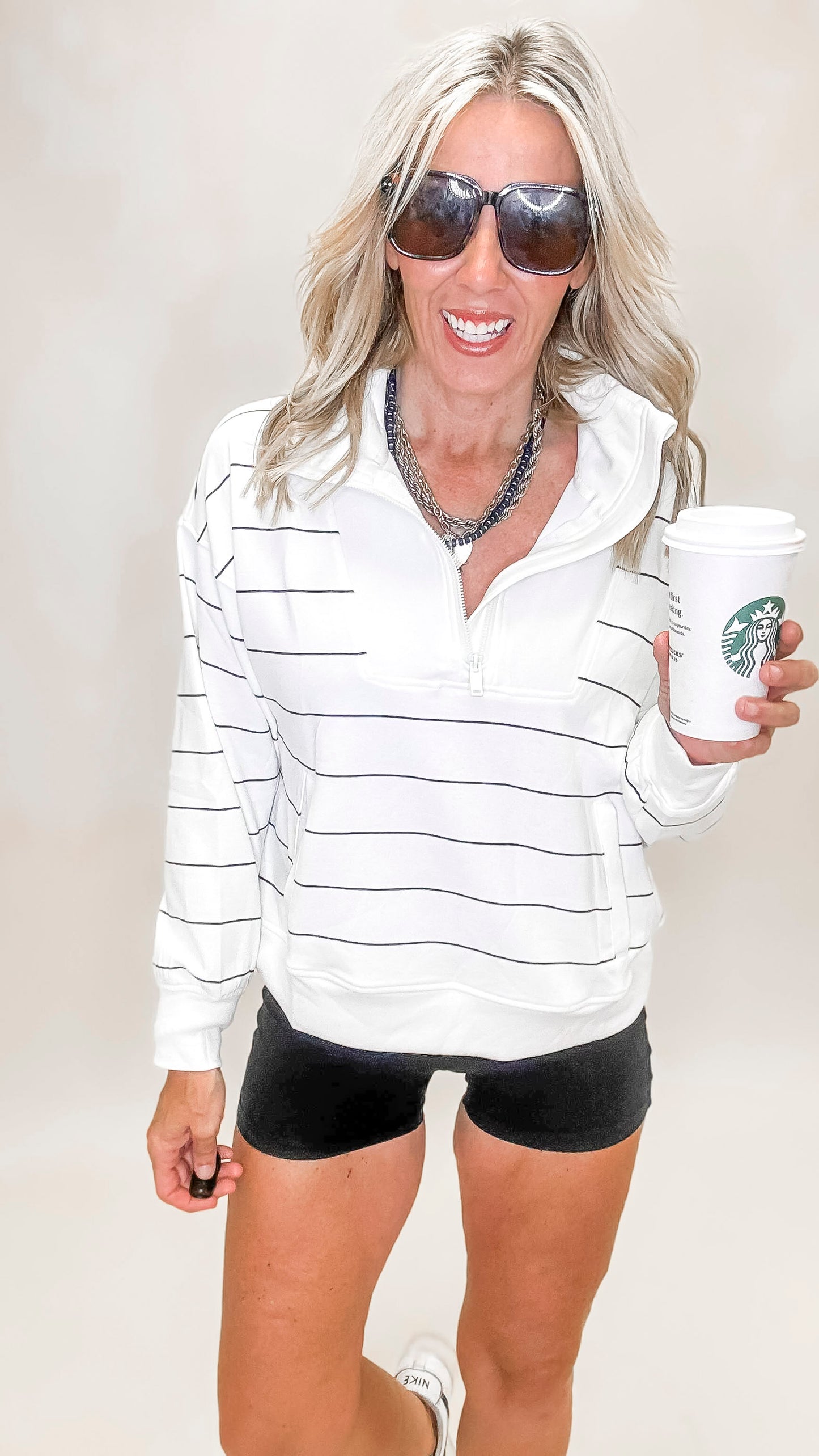 Women's white stripe pullover featuring a quarter zip front, drop shoulders, and modern mock neck.
