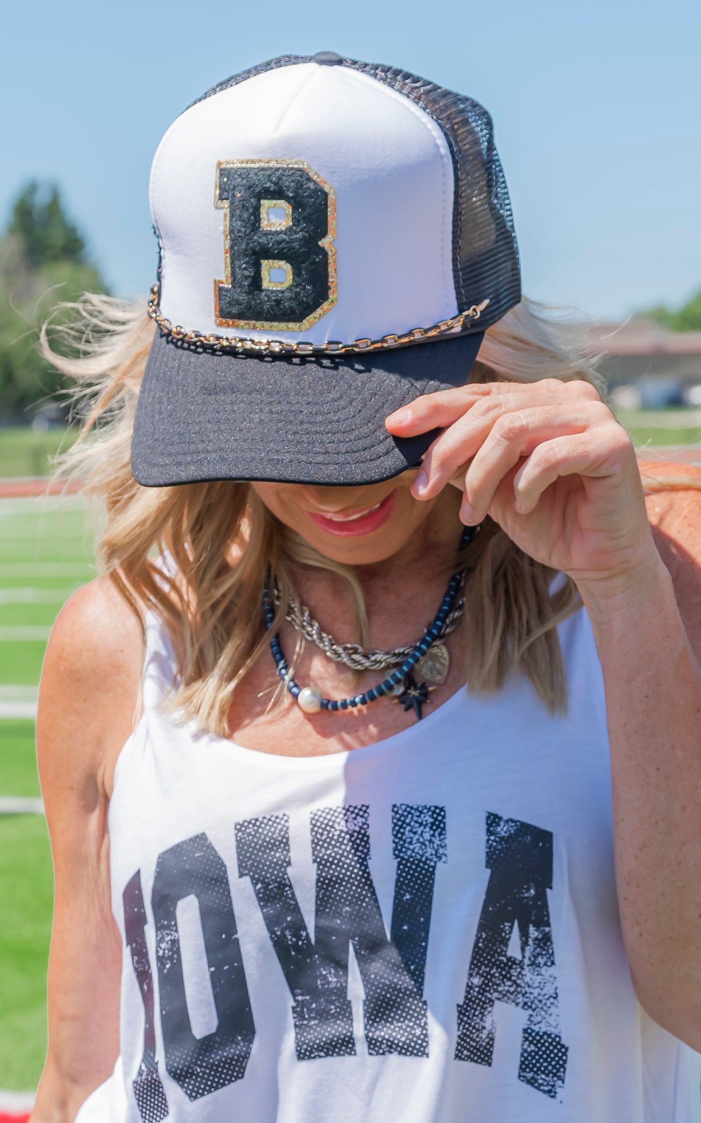 Person wearing a cap with a large 'B' and a tank top with 'IOWA' text, outdoors.