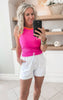 Close-up of white shorts styled with fuschia tank top and sandals for an everyday look
